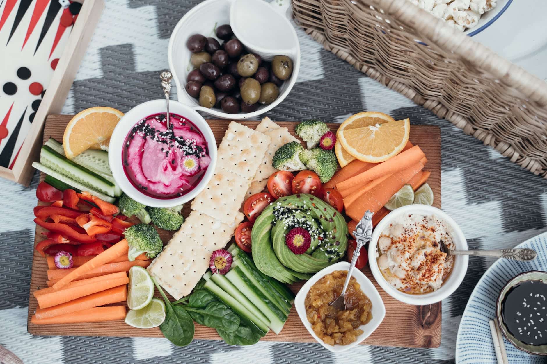 Brett mit Humus, Crackern und verschiedenen Gemüsesorten